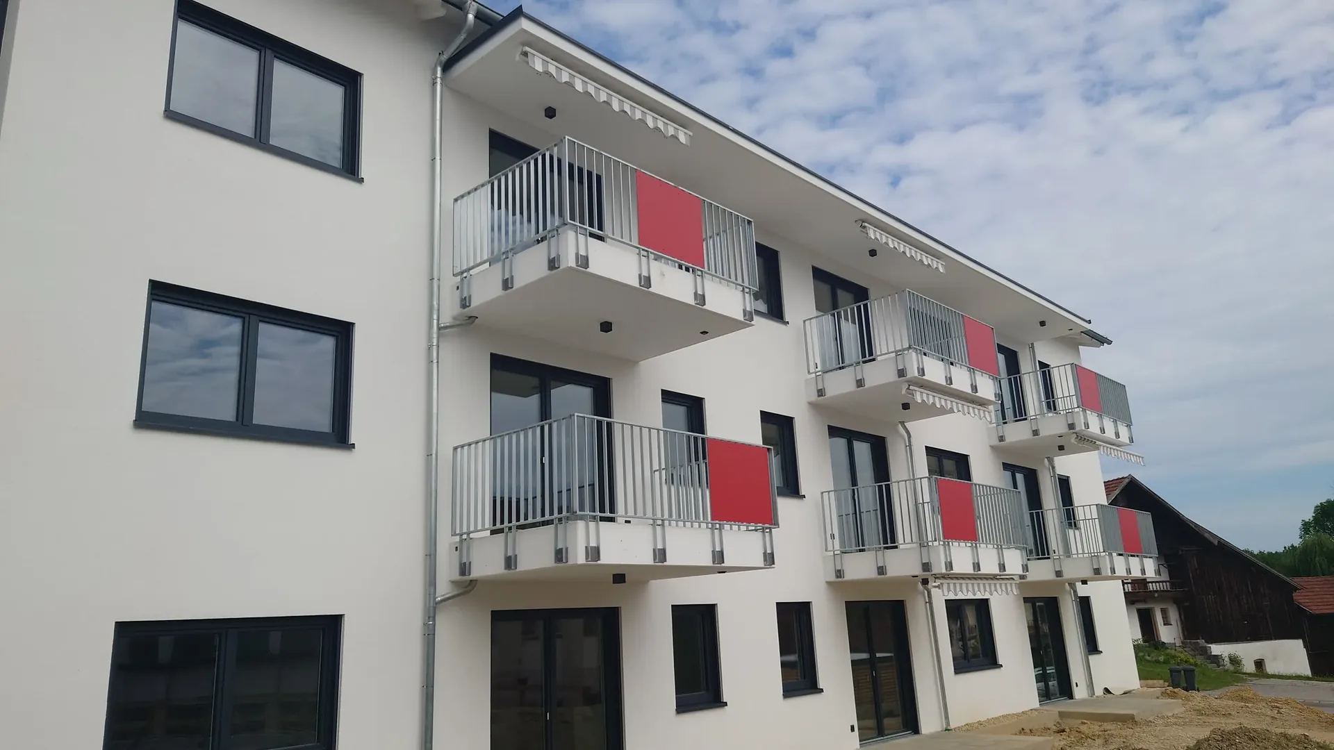 Balkongeländer aus verzinktem Stahl mit roter HPL-Füllung an einem Pflegezentrum